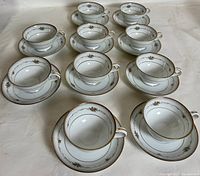 Photo showing all ten teacups with matching saucers, arranged on a flat surface.