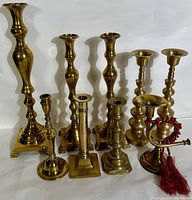 Full view of the assorted brass candlesticks showing various heights and styles arranged together