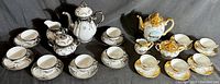 Full shot of two tea sets including teapots, creamers, sugar bowls, cups and saucers, displayed together
