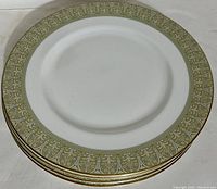 Stack of six Royal Doulton Sonnet dinner plates showcasing pale green and gold border pattern.