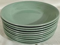 Stack of ten light green ceramic bowls showing top rims and side profile