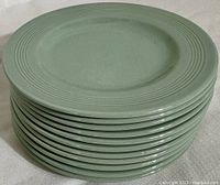 Stack of 12 green Woods Ware Beryl side plates showing rim design and uniform color.
