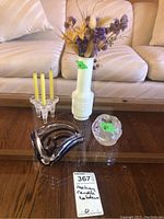 Overview of all items: ashtray, ceramic vase with faux flowers, two glass candleholders with candles on a glass table