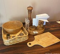 Photo showing assorted baskets, napkin rings, cutting board, and pepper mills on wood table