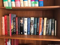 Two wooden shelves filled with different titles of fiction and nonfiction books. The spines show authors such as Pierre Berton, Dan Brown, Margaret Atwood, Margaret Thatcher, and Ann-Marie MacDonald.