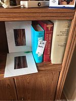 Photo of three books on a wooden shelf showing The Complete Dog Book, Medical and Health Encyclopedia, and The Random House Dictionary