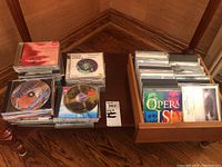 Photo showing the collection of CDs stacked and organized, with a visible wooden box on the right containing several CDs with classical and opera music titles.