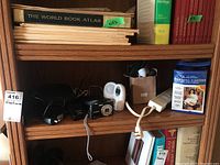 Wooden shelf with Panasonic Lumix camera charger, Vtech baby monitor, power strip, warming footies and books.
