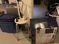 Photo showing round adjustable shower seat, walking sticks, rolled tensor bandage, bed risers, and boxed toilet seat