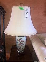 One of the two matching ceramic table lamps with floral decoration and cream fabric shade.