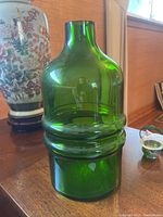Front angle view of the green glass vase showing the shape, texture, and Rosenthal sticker on the lower part