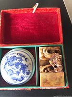 The top view of the open red box containing the dragon carved name stamp and closed porcelain ink pad with blue dragon design lid.