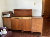Front view of stereo console with both top lids open revealing turntable and tuner