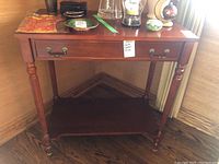 Front view of Bombay Company faux wood side table, showing drawer, lower shelf, and turned legs