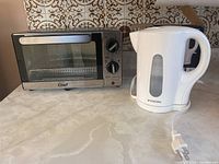 Master Chef toaster oven and Proctor Silex electric kettle side by side on countertop.