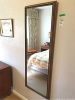 Full length rectangular wall mirror hung on a wall, showing the entire mirror and surrounding area.