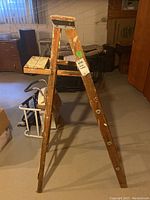 Wooden step ladder leaning in basement showing wear and paint chipping.