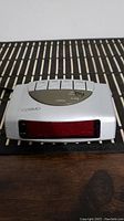 Front view of silver Cosmo alarm clock with red LED display and white control buttons on top