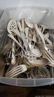 Plastic container with assorted old silverware including spoons, forks, knives, and serving utensils in various ornate styles.