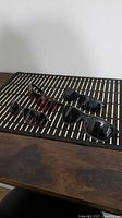 Photo showing four pairs of sunglasses placed on a black and white patterned mat on a wooden table.
