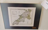 Framed antique map overall showing the full map and metal frame with dark matte border and brass label plate.