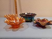 Four carnival glass bowls displayed together showing color and shape variety.