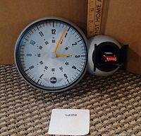 Photo showing BMW Mini cuckoo clock with round clock face featuring MINI logo and miniature red Mini car inside a small garage door to the side.