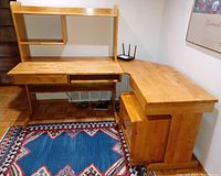 Wide view of wooden corner computer desk with hutch, drawers, keyboard shelf, and file cabinet on wheels placed on patterned rug.