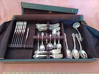 Full flatware set arranged inside zippered storage box showing compartments and straps.