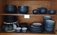 Full set arranged on kitchen shelf showing bowls, plates, cups on a rotating rack, and saucers.