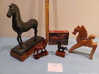 Lot with five horse-related items: large bronze horse on wooden base with stains, small bronze horse not attached to base, carved wood horse, ceramic horse, and box of note cards.