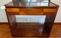 Front view of sideboard showing wood veneer geometric drawer front and glass shelf
