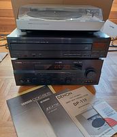 Stacked audio equipment showing Denon turntable on top, Yamaha CD changer below it, Yamaha AV receiver at bottom, with manuals laid out in front.
