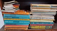 Left stack of vintage Ford shop manuals showing various bright colored spines with model years and types