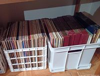 Two crates filled with vinyl records stored vertically, some record covers showing age-related wear and discoloration, possibly mildew or mold present. Mixed genres and RPM formats likely.