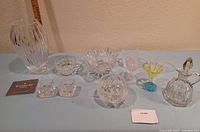 Wide view of the collection including Waterford vase, signed McNicsney bowl, candleholders, tumblers, goblets, decorative flower piece and carafe.