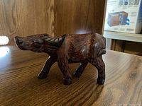 Side view of wooden carved wildebeest showcasing detailed carving and fur patterns.