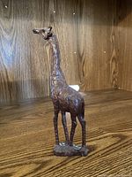 Front view of the wooden giraffe carving showing detailed texture and natural wood color on a wood background.