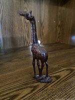 Side angle view of the wooden giraffe carving displaying detailed carving and polished wood surface.