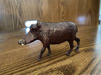 Side view of the wooden African warthog carving showing detailed textures and proportions.