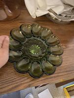 Green devilled egg tray with egg-shaped compartments and starburst base pattern, held by hand