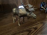 Brass moose figurine with detailed antlers standing on a wooden surface