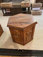 Hexagonal wooden side table from an angled front view showing top and two doors with metal ring pulls.