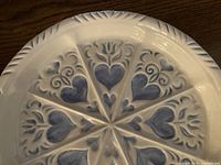 Close up image of one of the blue heart-patterned pie plates showing the detailed design and textured rim.