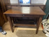 Full view of the solid wood table showing rectangular top, straight legs, lower shelf, and drawer pull detail.