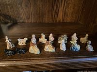 Full display of 16 Tetley Tea collectible figurines on wooden shelf, including various children, adults, and dogs in vintage style.