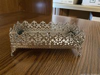Filigree silver butter dish with detailed openwork floral pattern and decorative feet.