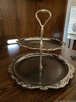 Photo of 2-tier silver serving dish with scalloped edges and handle showing overall condition and details.