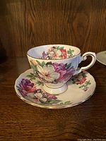 Azalea pattern bone china teacup and saucer with pink, purple, and white flowers and gold trim.