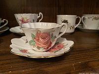 Side view of Coral Rose bone china teacup and saucer with scalloped edge and rose floral pattern.